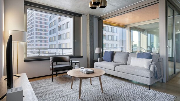 Ein modernes Wohnzimmer mit einer Couch, einem Sessel, einem Couchtisch und einem Fernseher.