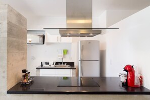 A modern kitchen with a stainless steel refrigerator, a built-in oven, and a black countertop.