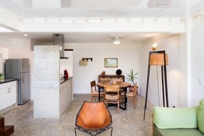 A modern kitchen with a refrigerator, stove, and dining area with chairs and a table.