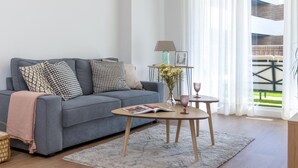 A modern living room with a grey sofa, a small wooden coffee table, and a view of an outdoor balcony. - Misterhost La Florida Pool & Private Terrace (Sevilla)
