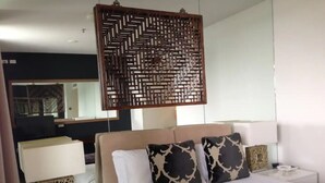 A hotel room with a bed, bedside tables, a decorative screen, and a mirror.