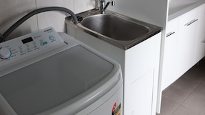 A laundry area with a washing machine, a dryer, and a sink. - The Court House Hotel (Gunnedah)
