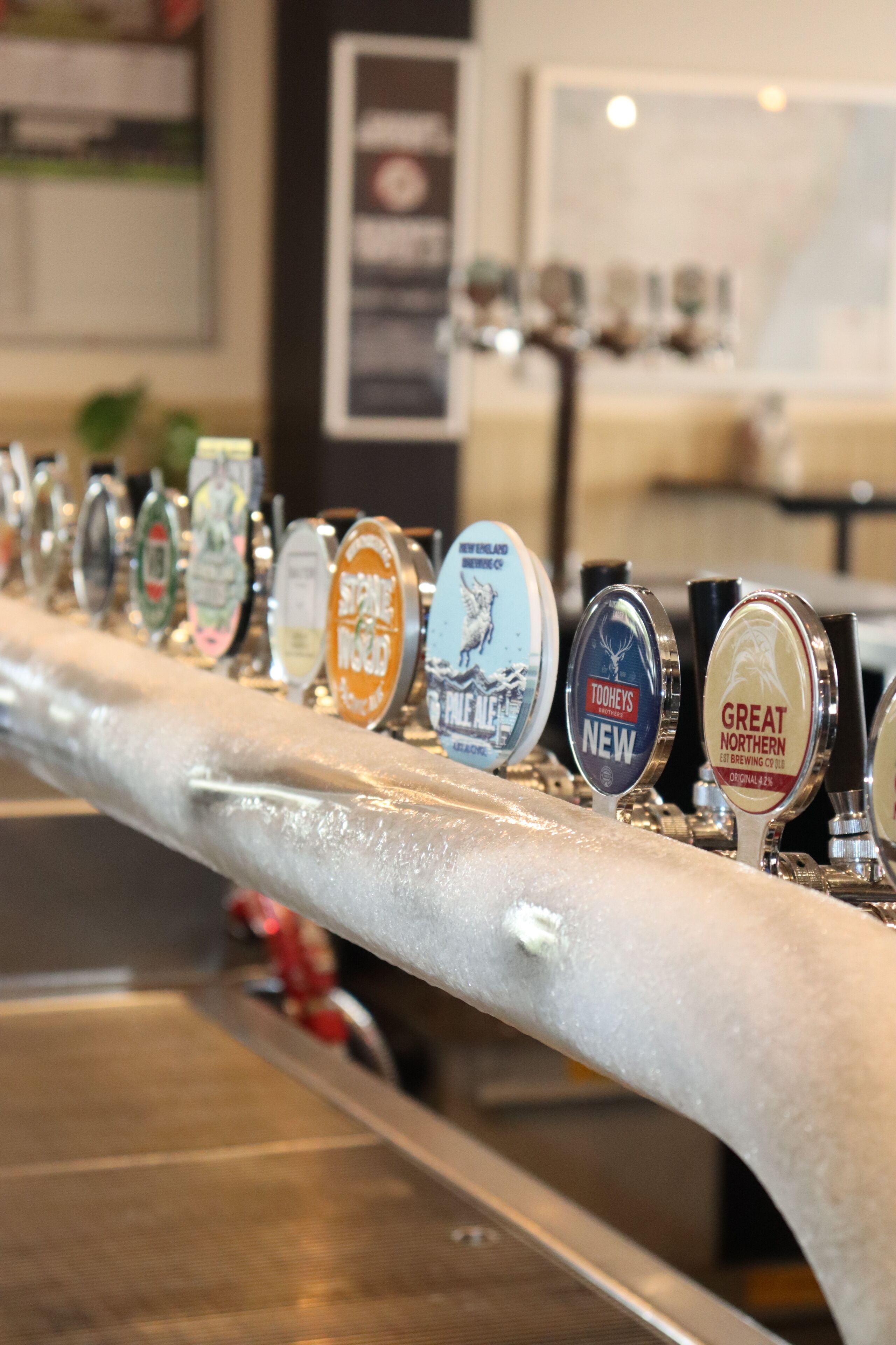 A bar with a row of beer taps, including brands like Great Northern and Toorley's New.