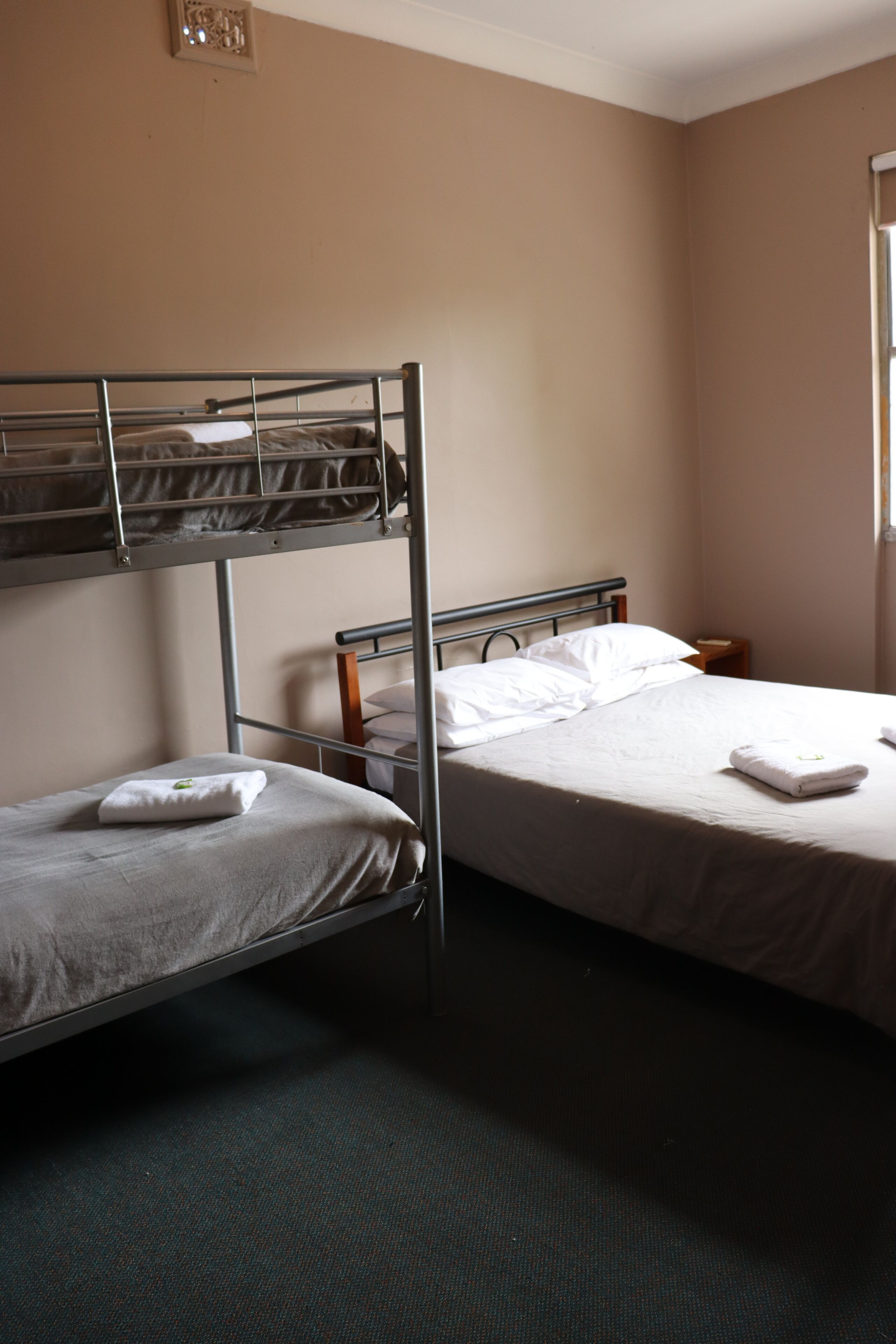 A room with two beds, one on the floor and one on a bunk.