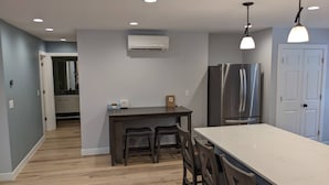 Een moderne keuken met een centraal eiland, donkerhouten stoelen, een roestvrijstalen koelkast en inbouwspots.