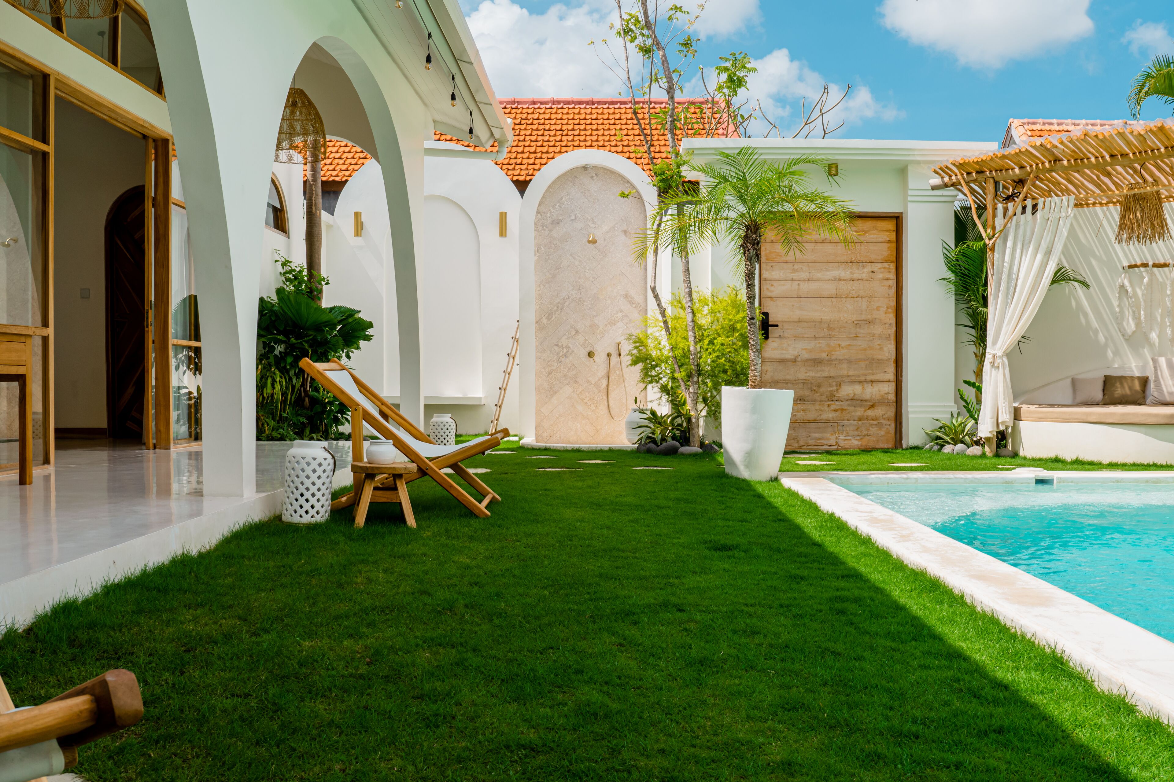 A well-maintained pool area with a clear view of the pool, a grassy lawn, and a wooden deck.