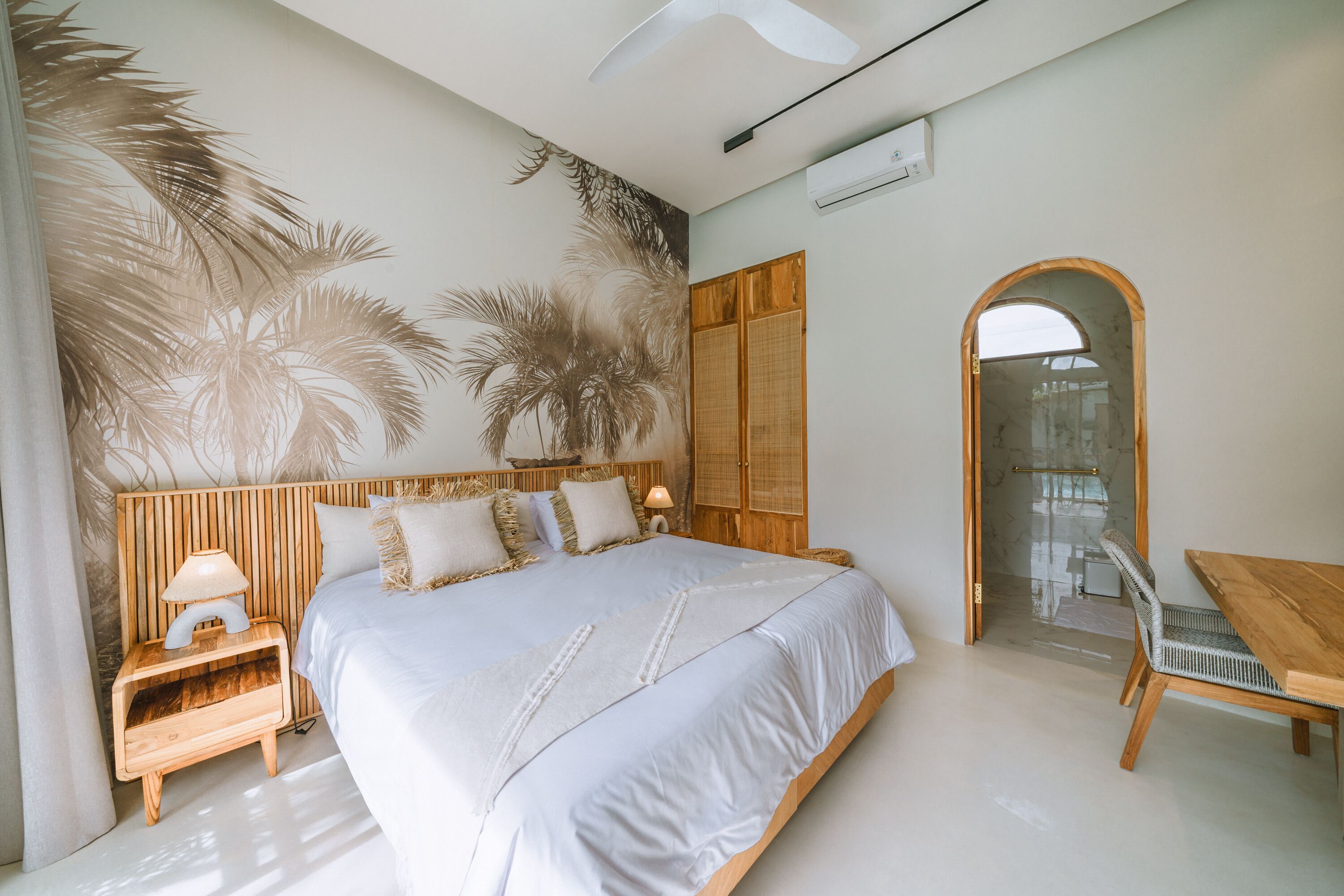 A bedroom with a large bed, wooden headboard, and a nightstand with a lamp.