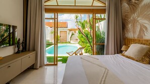 Een slaapkamer met een groot bed, een televisie en uitzicht op een zwembad en groen.