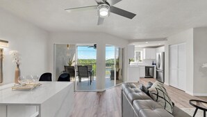 A spacious living area with a modern kitchen, a dining table, and a sofa. - Jupiter Bay Resort Condo, steps to the beach! Comfortably sleeps family of 4! (Jupiter)