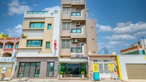 A multi-story building with a modern design, featuring a storefront with glass doors and windows, and a visible entrance. - Chunfa B&B (Huxi)
