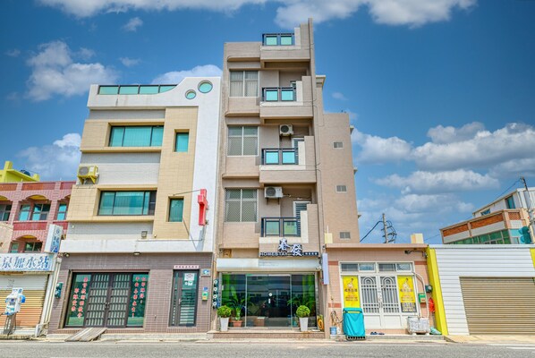 A multi-story building with a modern design, featuring a storefront with glass doors and windows, and a visible entrance. - Chunfa B&B (Huxi)