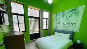 A room with a bed, a desk, a window with curtains, and a wall with a tropical-themed poster. - Chunfa B&B (Huxi)