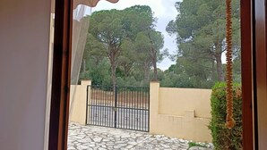 A view through a doorway to a courtyard with a stone floor, a metal gate, and a yellow wall. - Summer house close to the forest in L'Escala.HUTG-071512 (l'Escala)