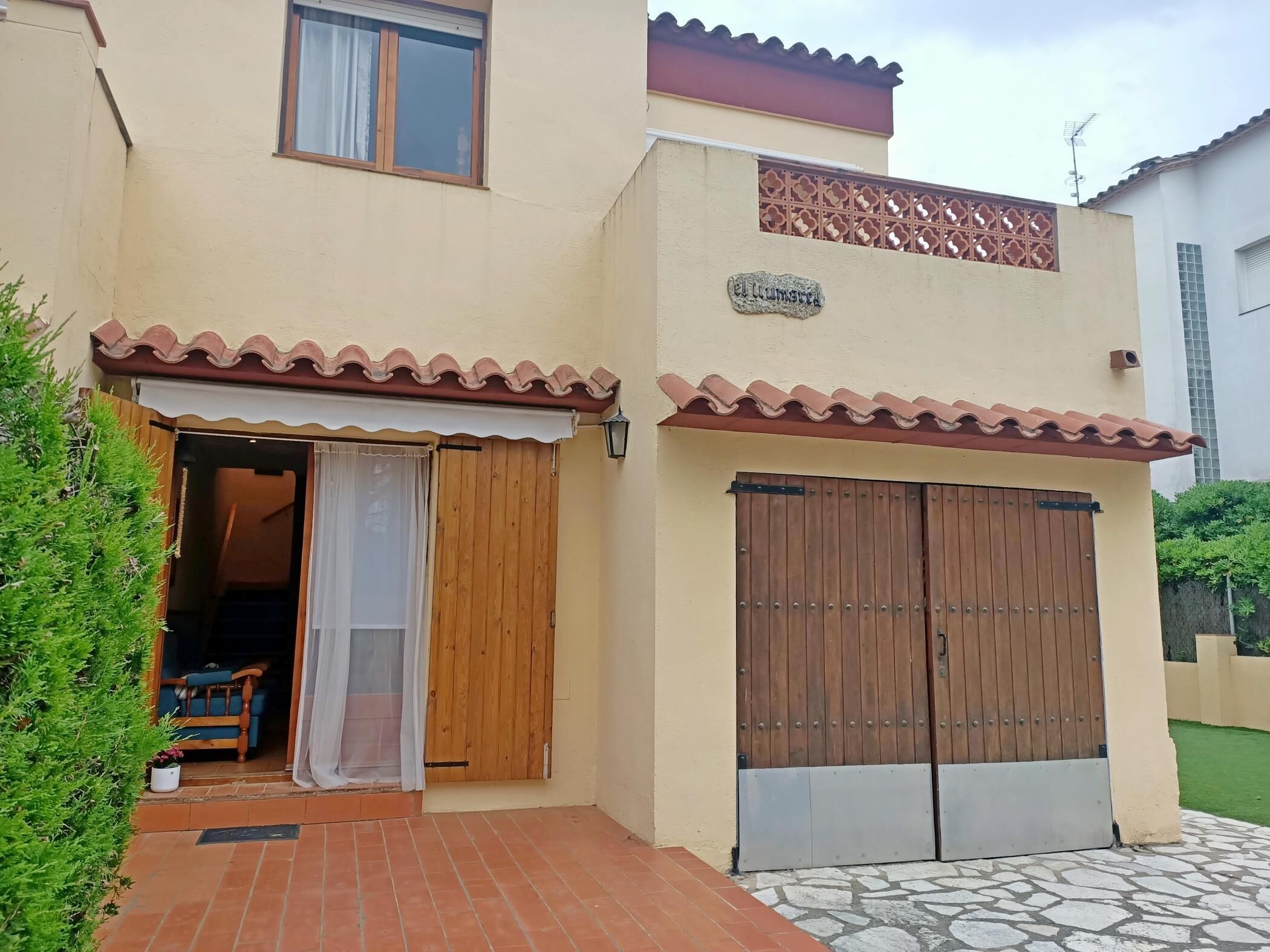 Un bâtiment à deux étages avec une façade beige, une porte en bois et un patio carrelé.