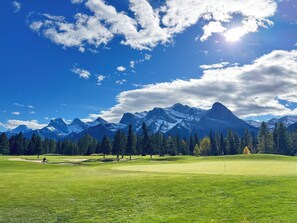 Un parcours de golf avec une chaîne de montagnes en arrière-plan.