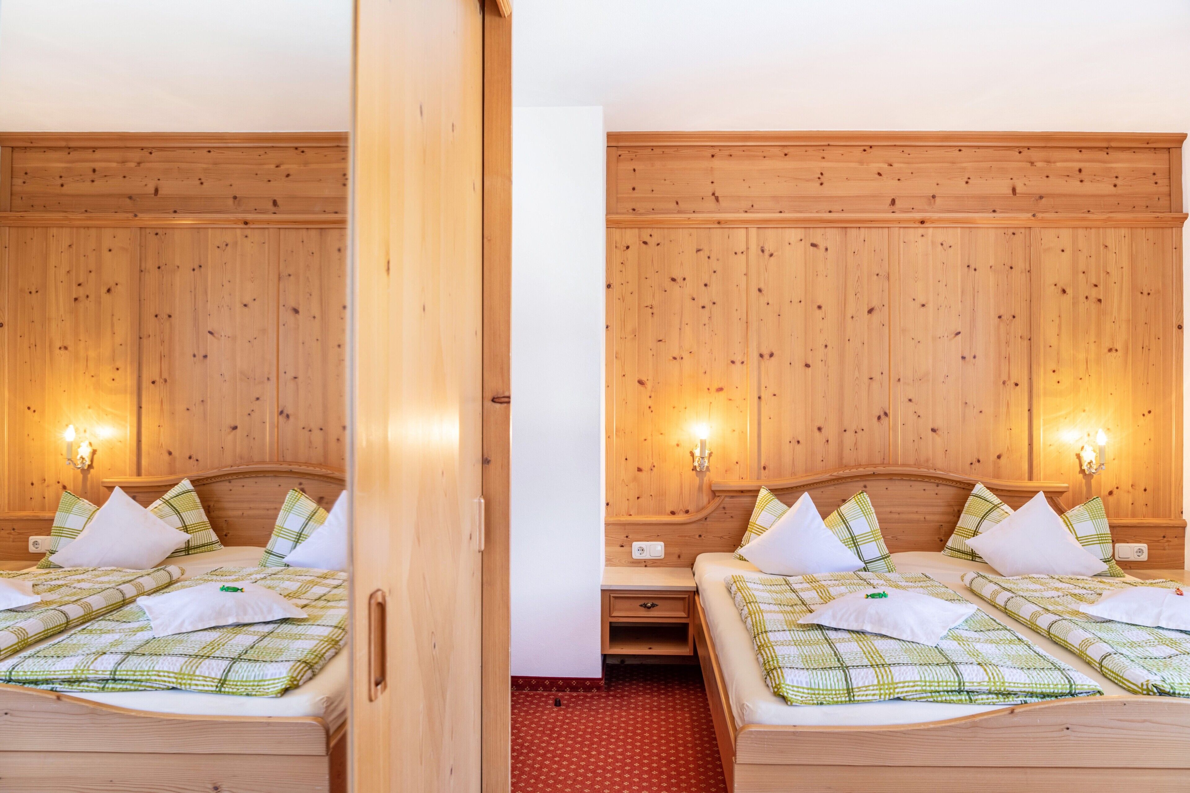 Une pièce aux murs recouverts de miroirs, avec deux lits, des murs en bois et des lampes fixées au mur.
