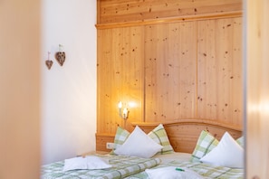 Une pièce aux murs lambrés, avec un lit, des oreillers et un luminaire fixé au mur.