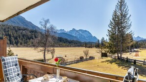 A balcony with a table set for two, overlooking a mountainous landscape.