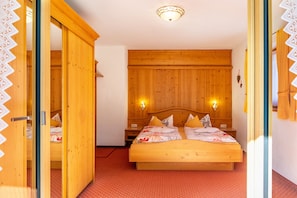 A wooden bedroom with a bed, two bedside tables, and a wall-mounted light fixture.