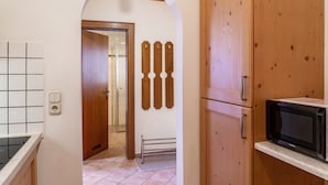 Una cocina con armarios de madera, microondas y salpicadero de azulejos.