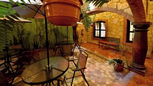 An indoor patio area with tables and chairs, potted plants, and a stone wall.