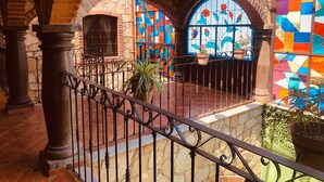 A courtyard with stone arches, a tiled floor, and a wrought iron railing.