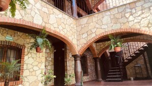 A courtyard with stone walls, multiple balconies, and potted plants.