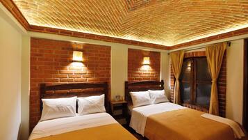 Habitación de hotel con dos camas, paredes de ladrillo y techo de madera.