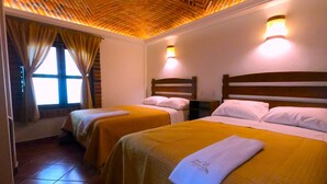 A hotel room with two beds, a brick ceiling, and a window with curtains.