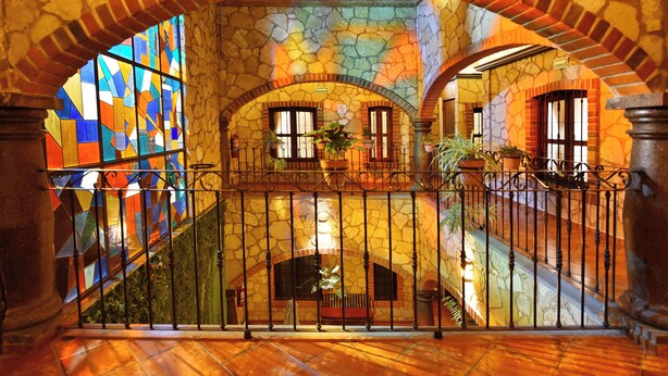 A stone interior with a staircase, arched ceilings, and a stained glass window.