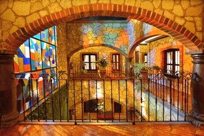 A stone interior with a staircase, arched ceilings, and a stained glass window. - Hotel Santa Irene (San Pedro Cholula)
