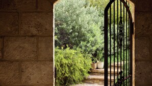 An arched stone doorway leading to a garden with a metal gate.