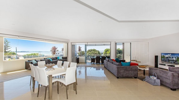 Enjoy a panoramic sea view from the spacious living area with a sofa, dining table, and flat-screen TV.