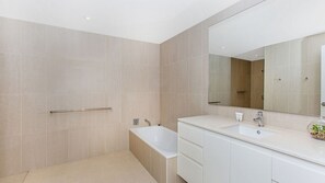 Bathroom features a large bathtub, vanity with sink, and mirror.