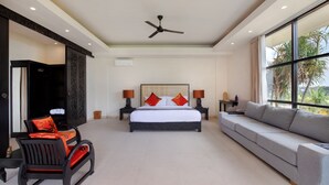 Ein geräumiges Schlafzimmer mit einem großen Bett, einer Schlafcouch, einem Schaukelstuhl und einem Deckenventilator.
