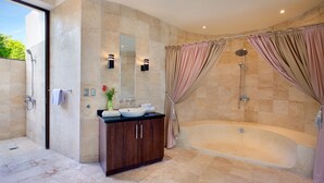 Ein modernes Badezimmer mit einer großen Badewanne, einer Duschkabine und einem Waschtisch mit Spiegel.