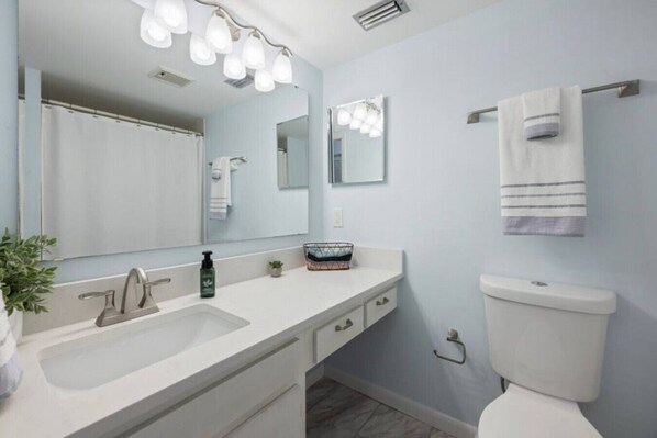 Une salle de bain moderne avec un lavabo blanc, un grand miroir et des toilettes.
