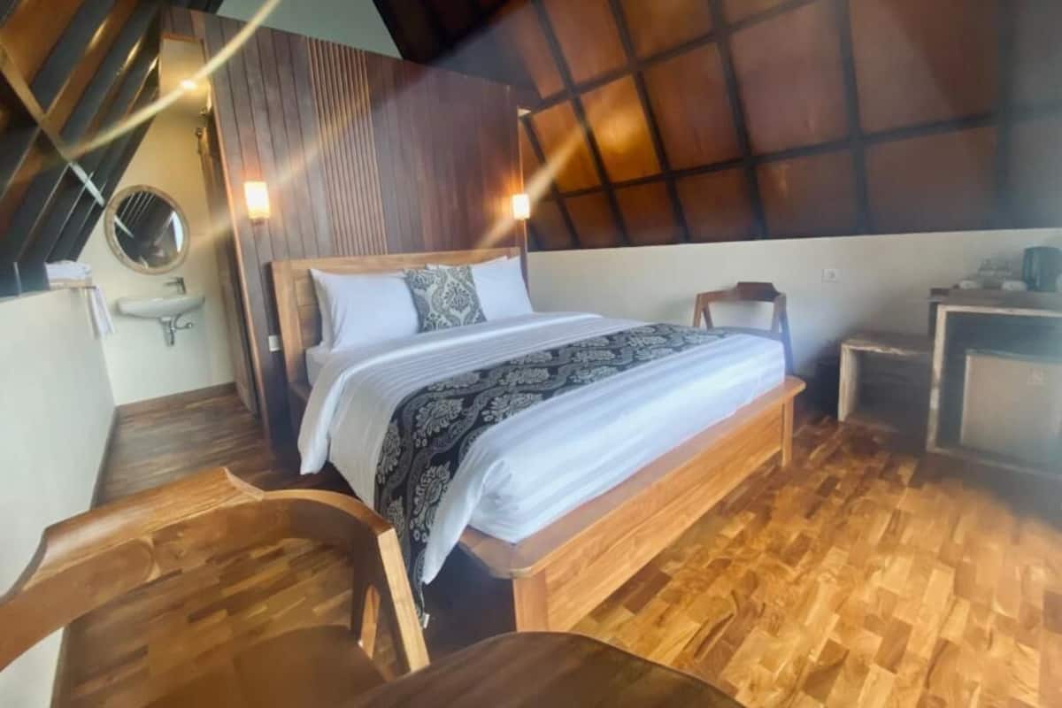 A bedroom with a wooden bed, a small bedside table, and a chair.