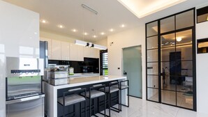 A modern kitchen with a central island, bar stools, and a built-in oven. - New Wunuanzoo (Jiaoxi)