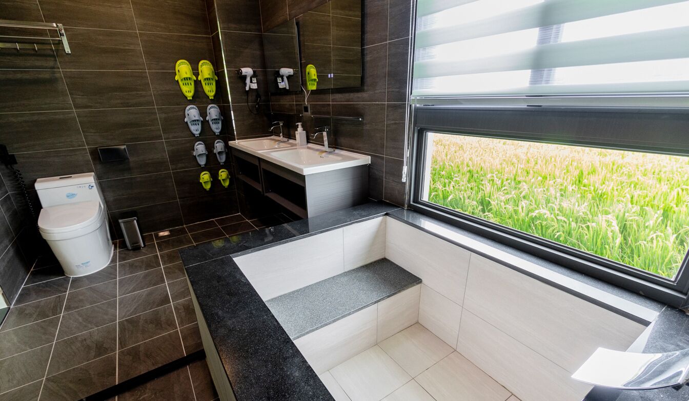 A modern bathroom with a large window, a bathtub, and a vanity with a mirror.