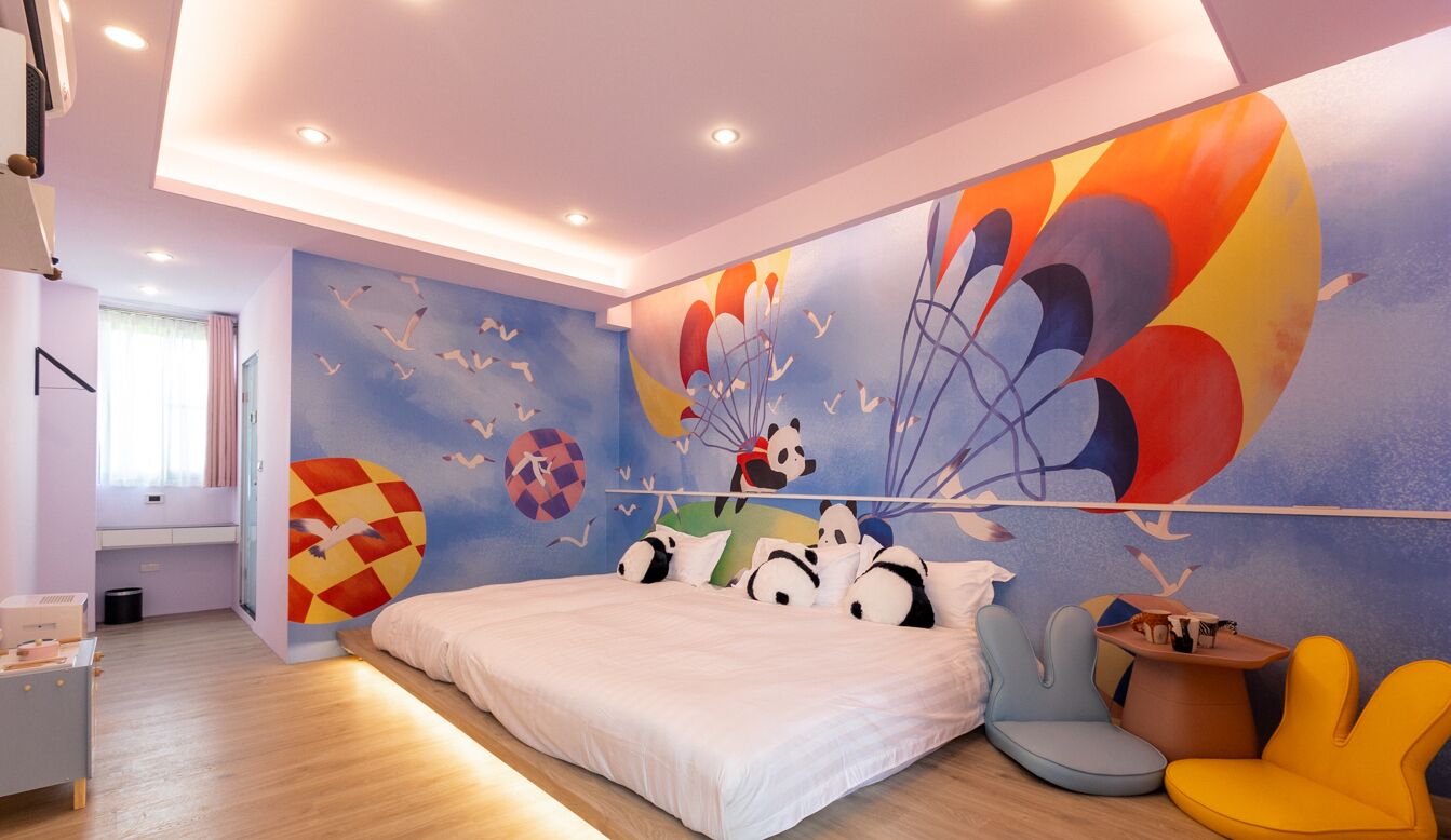 Un dormitorio con una cama grande, un mural colorido y una ventana con cortinas.