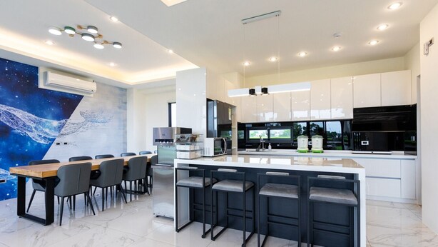 A modern kitchen with a central island, bar stools, a dining table with chairs, and a large mural on the wall. - New Wunuanzoo (Jiaoxi)