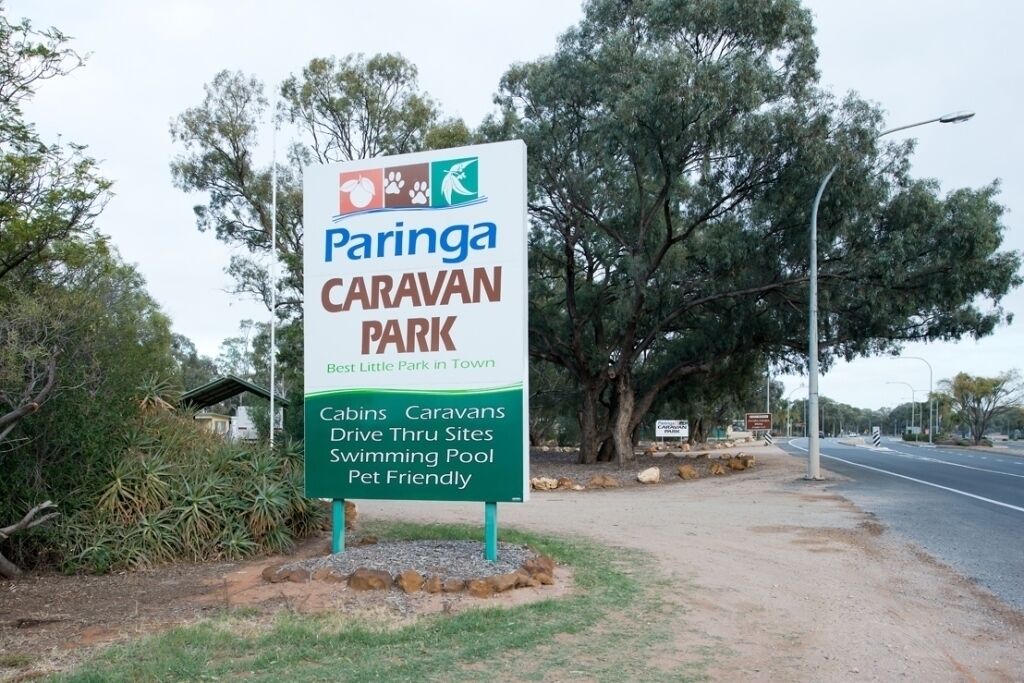 A sign for Paringa Caravan Park, highlighting features like cabins, caravans, drive thru sites, a swimming pool, and pet-friendly facilities.
