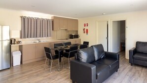 A modern apartment with a kitchen, dining area, and two black leather sofas. - Paringa Caravan Park (Paringa)