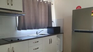 A kitchen with white cabinets, a stainless steel refrigerator, a microwave, and a sink. - Paringa Caravan Park (Paringa)