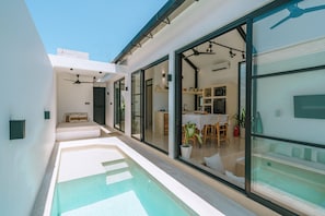 A modern house with a swimming pool, large glass doors, and a dining area. - Villa Cha Cha  (Canggu)