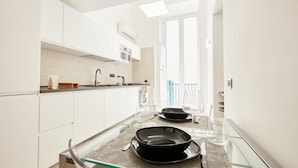 A modern kitchen with white cabinetry, a glass-top dining table, and a view of the balcony. - Studio Duplex at National Museum (Naples)