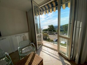 Een balkon met uitzicht op een meer en heuvels, een stoel en een tafel.