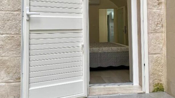 A room with a bed, a window, and a door leading to an outdoor area. - Grandma Lucia's house (Monopoli)