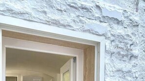 A hallway leading to a kitchen with a white textured wall and a wooden floor. - Grandma Lucia's house (Monopoli)